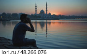 A lone mourner sitting by a river at twilight, his reflection blurred in the water as he whispers prayers for the martyrs of Karba. Стоковое AI-видео, аниматор Sergey Grishin / Фотобанк Лори