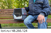 An elderly man holds a cat in a carrier. Pet transportation, traveling with a pet. A close friend of an elderly man. Стоковое фото, фотограф Терехова Марина / Фотобанк Лори