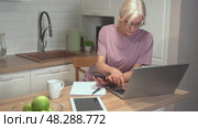 Woman multitasking in modern kitchen with laptop and smartphone. Стоковое видео, видеограф Владимир Федоров / Фотобанк Лори