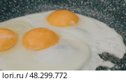 The egg sizzles as it hits the hot pan, the clear liquid slowly turning white and firm around the bright yellow yolk. Стоковое видео, видеограф Алексей Круковский / Фотобанк Лори