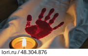 A close-up of a bloodied handprint on a white cloth, symbolizing sacrifice, illuminated by the dim glow of a single oil lamp. Стоковое AI-видео, аниматор Sergey Grishin / Фотобанк Лори