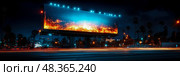 The digital billboard emits bright colors and patterns, illuminating the night sky in a lively city environment filled with passing cars. Стоковое AI-изображение, AI-художник Данила Большаков / Фотобанк Лори