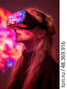A young woman engages with virtual reality equipment, captivated by an immersive digital world illuminated by bright, colorful lights. Стоковое AI-изображение, AI-художник Данила Большаков / Фотобанк Лори