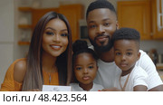 A happy family gathers in their warm kitchen, celebrating a special occasion with smiles, close proximity, and a heartfelt gesture. Стоковое AI-изображение, AI-художник Данила Большаков / Фотобанк Лори