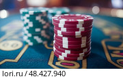 Colorful stacks of red and green poker chips sit on a felt table as players engage in an intense casino gaming experience. Стоковое AI-изображение, AI-художник Данила Большаков / Фотобанк Лори