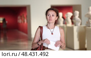 Interested woman looking closely at classical statues in museum and holding tour sheet in hands. Стоковое видео, видеограф Яков Филимонов / Фотобанк Лори