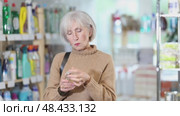 Elderly housewife chooses perfume or aromatic incense in a supermarket. Стоковое видео, видеограф Яков Филимонов / Фотобанк Лори