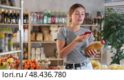 Young woman uses phone to scan peach juice, read the composition and calorie content of the drink. Customer in a supermarket scans the qr code of the juice and pays through the banking app. Стоковое видео, видеограф Яков Филимонов / Фотобанк Лори