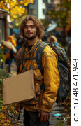 Urban Nomad: a Wanderer with Cardboard and Backpack, Portrait of survival and self-discovery on the Road. Стоковое AI-изображение, AI-художник Данила Большаков / Фотобанк Лори