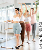 Young girl practicing third position holding by ballet barre. Стоковое фото, фотограф Яков Филимонов / Фотобанк Лори