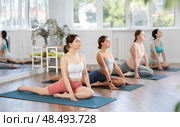 Young girl doing Eka Pada Rajakapotasana with group in yoga studio. Стоковое фото, фотограф Яков Филимонов / Фотобанк Лори