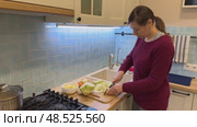 A housewife cuts cabbage on a wooden soup board in the kitchen. Стоковое видео, видеограф Ирина Старикова / Фотобанк Лори