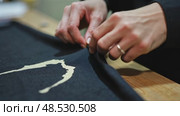A close-up of a woman's hands sewing a black cloth banner, her fingers trembling slightly as she prepares for the Ashura process. Стоковое AI-видео, аниматор Sergey Grishin / Фотобанк Лори