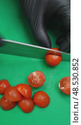 Gloved hands slicing cherry tomatoes on a green cutting board, then adding them to a metal bowl containing sliced cucumbers. Стоковое видео, видеограф Данил Руденко / Фотобанк Лори