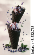 Two ice cream cones with blueberry ice cream and blueberry sauce. Стоковое AI-изображение, AI-художник Ярославский Максим / Фотобанк Лори
