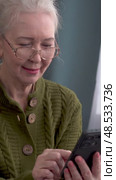 Elderly woman engages with smartphone technology in home setting. Стоковое видео, видеограф Владимир Федоров / Фотобанк Лори