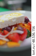 Feta cheese crowning greek salad, tomatoes, cucumbers, onions, olives, peppers glistening under streaming olive oil. Стоковое видео, видеограф Данил Руденко / Фотобанк Лори