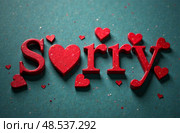 Red letters spelling "Sorry" with a heart symbol, surrounded by small red hearts on a textured teal background, conveying a heartfelt apology and emotional connection. Стоковое AI-изображение, AI-художник Котова / Фотобанк Лори