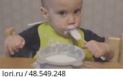 funny baby toddler learning to eat with spoon, child learn eating use teaspoon. Стоковое видео, видеограф Olesia Kondrateva / Фотобанк Лори