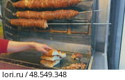 Street food vendor slicing and grilling traditional Turkish kokorec at a local food stall. Стоковое видео, видеограф Дмитрий Наумов / Фотобанк Лори