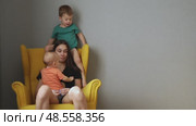 tired exhausted young mother sitting disturb in chair with two naughty children. Стоковое видео, видеограф Olesia Kondrateva / Фотобанк Лори