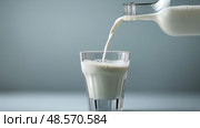 Pouring fresh milk into a clear glass creating bubbles and foam. При наливании свежего молока в прозрачный стакан образуются пузырьки и пена. Стоковое AI-изображение, AI-художник Katsiaryna Repich / Фотобанк Лори