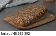 Homemade rye bread sliced on a wooden cutting board in a modern kitchen setting. Стоковое видео, видеограф Наталия Попова / Фотобанк Лори