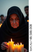 An Elderly Woman, Dressed in a Black Chador, is Lighting Candles at Dusk. Стоковое AI-изображение, AI-художник Sergey Grishin / Фотобанк Лори
