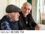 Мужчина улыбается. Пенсионеры с азартом играют в нарды. Активное долголетие. Счастливая старость. Редакционное фото, фотограф Evgenia Shevardina / Фотобанк Лори