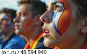 A close-up of a fan's face painted with intricate colors team designs, their eyes wide with anticipation as they watch the match on a giant sport stadium. Стоковое AI-видео, аниматор Sergey Grishin / Фотобанк Лори
