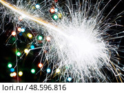 Bengal light flash on background christmas tree with garland lights. Abstract blurred backdrop. Стоковое фото, фотограф Зарифа Арсланова / Фотобанк Лори