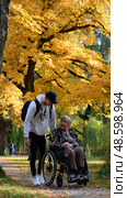 A man is helping an elderly woman in a wheelchair. Стоковое AI-изображение, AI-художник Ярославский Максим / Фотобанк Лори