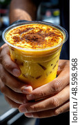 A person is holding a cup of a drink with a brownish color. Стоковое AI-изображение, AI-художник Ярославский Максим / Фотобанк Лори
