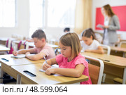 Diligent preteen schoolgirl making notes of teacher lecture. Стоковое фото, фотограф Яков Филимонов / Фотобанк Лори