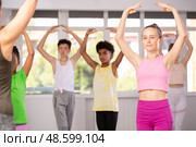 Positive teenage girl practicing ballet positions standing in row with others. Стоковое фото, фотограф Яков Филимонов / Фотобанк Лори