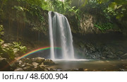 Powerful waterfall cascades down rocky cliffs, with vibrant rainbow forming in middle of rushing water, creating stunning natural spectacle. Стоковое AI-видео, аниматор Данила Большаков / Фотобанк Лори