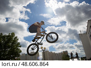 Belarus, Gomel, June 24, 2018. Central park. Extreme cycling.A dangerous trick on a bicycle against the backdrop of the city.A teenager on an extreme bicycle against the sky performs a jump. Редакционное фото, фотограф Лазаренко Светлана / Фотобанк Лори