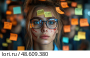 A young woman with glasses and facial scars stares intently at colorful sticky notes on a wall in a low-lit creative workspace. Стоковое AI-изображение, AI-художник Данила Большаков / Фотобанк Лори