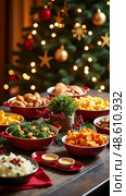 Festive Table Setup With Various Dishes, Christmas Decor, and a Lush Tree, Inviting for Gatherings and Holiday Catering. Стоковое AI-изображение, AI-художник Sergey Grishin / Фотобанк Лори