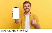 Этот молодой человек излучает радость, демонстрируя чистый экран смартфона с неподдельным энтузиазмом, что идеально подходит для демонстрации приложений, концепций мобильных технологий или рекламных кампаний. Стоковое AI-изображение, AI-художник Никита Мурашов / Фотобанк Лори