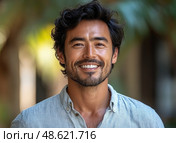 A cheerful man with curly hair is smiling warmly, dressed casually, enjoying the sunlight in a relaxed outdoor setting. Стоковое AI-изображение, AI-художник Данила Большаков / Фотобанк Лори