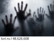 Shadows of desperation against a foggy glass surface in a dimly lit room. Тени отчаяния на фоне туманной стеклянной поверхности в тускло освещенной комнате. Стоковое AI-изображение, AI-художник Katsiaryna Repich / Фотобанк Лори