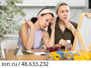 Two female friends examining faces in vanity mirror at home. Стоковое фото, фотограф Яков Филимонов / Фотобанк Лори