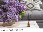 The aroma diffuser. Lilac-scented spring perfumes for the home in a glass bottle with chopsticks as an air freshener in the house. Aromatherapy, cozy atmosphere, comfort and relaxation. Стоковое фото, фотограф Photojuli / Фотобанк Лори