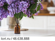 The aroma diffuser. Lilac-scented spring perfumes for the home in a glass bottle with chopsticks as an air freshener in the house. Aromatherapy, cozy atmosphere, comfort and relaxation. Стоковое фото, фотограф Photojuli / Фотобанк Лори