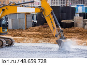 An excavator on a construction site in close-up. The excavator rams the crushed stone with a bucket for construction. Heavy machinery for construction and landscaping. Стоковое фото, фотограф Photojuli / Фотобанк Лори