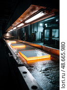 Hot metal ingots cooling down on industrial production line. Стоковое AI-изображение, AI-художник Юрий Поздников / Фотобанк Лори