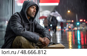 Homeless man sitting on cardboard seeking shelter from rain at night. Стоковое AI-изображение, AI-художник Юрий Поздников / Фотобанк Лори