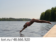 Athletic woman in swimsuit diving headfirst from a pier into the lake. Sunny summer day, dynamic outdoor action. Стоковое фото, фотограф Скоробогатова Е. / Фотобанк Лори