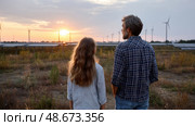 Father and daughter looking at solar panels. Solar farm and sunlight at sunset. Solar energy for green energy. Sustainable renewable energy. Photovoltaic power plant or solar park. Energy sustainability. Стоковое AI-изображение, AI-художник ALLA YURTAYEVA / Фотобанк Лори